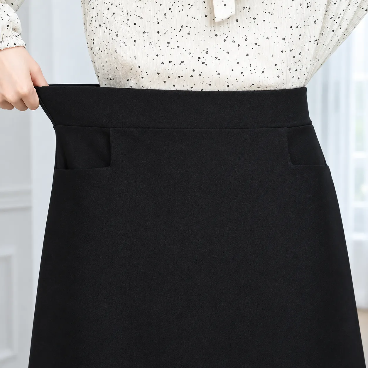 Close view of the black elastic waistband, two pocket openings and fine fabric construction